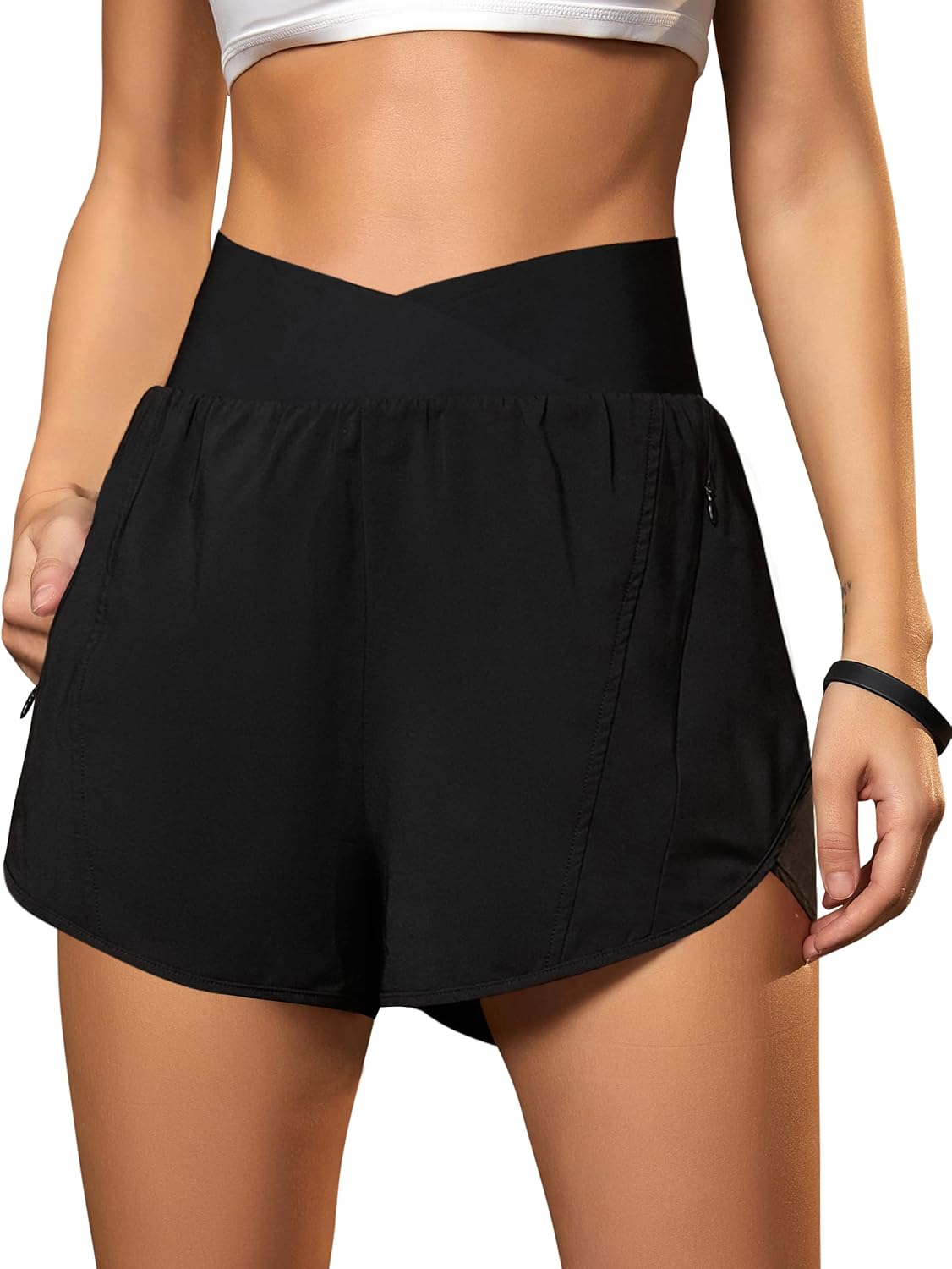 Black crossover high-waisted running shorts with zippered pockets and four-way stretch fabric — front